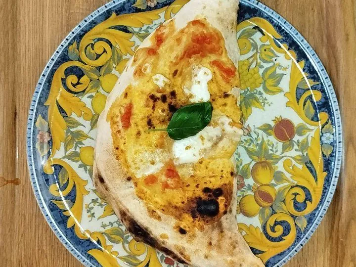 Un calzone al forno su un piatto di ceramica dipinta a mano